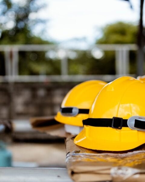 A row of yellow hard hats on a bench, symbolizing Thailand Construction Safety Standards and worker protection on site.