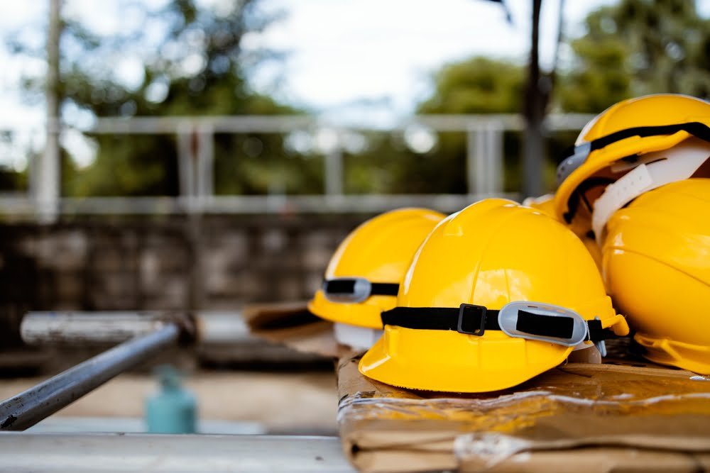 A row of yellow hard hats on a bench, symbolizing Thailand Construction Safety Standards and worker protection on site.