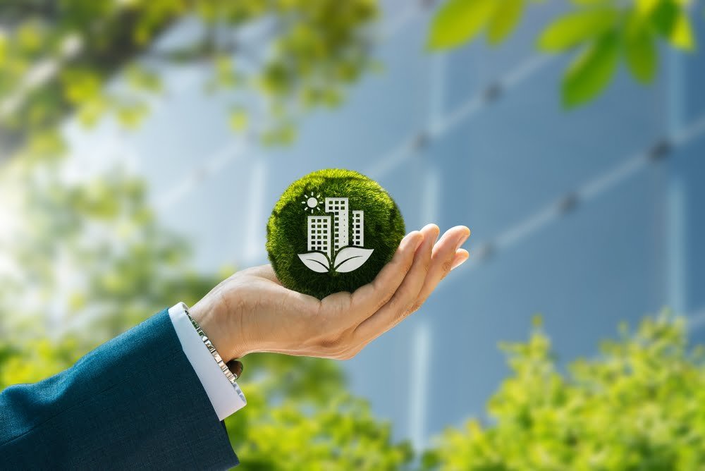 A businessman presents a green building concept, highlighting sustainable construction with a modern city skyline behind him.