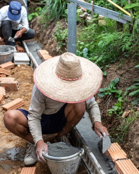 Two construction workers are laying down mason bricks, symbolising the shortage of Skilled Labor in Thailand Construction.