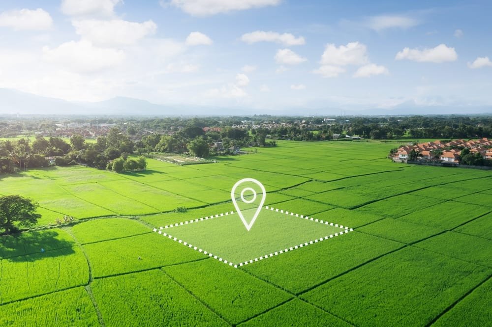 Aerial view of lush green rice paddies with a location pin graphic overlay, symbolising Thailand Infrastructure Investment.