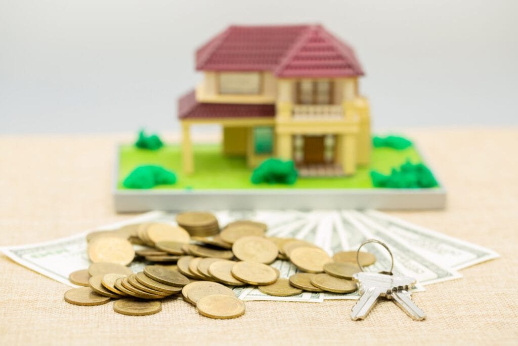 Real Estate Financing Thailand: Miniature house on money with keys in front, representing real estate investment.