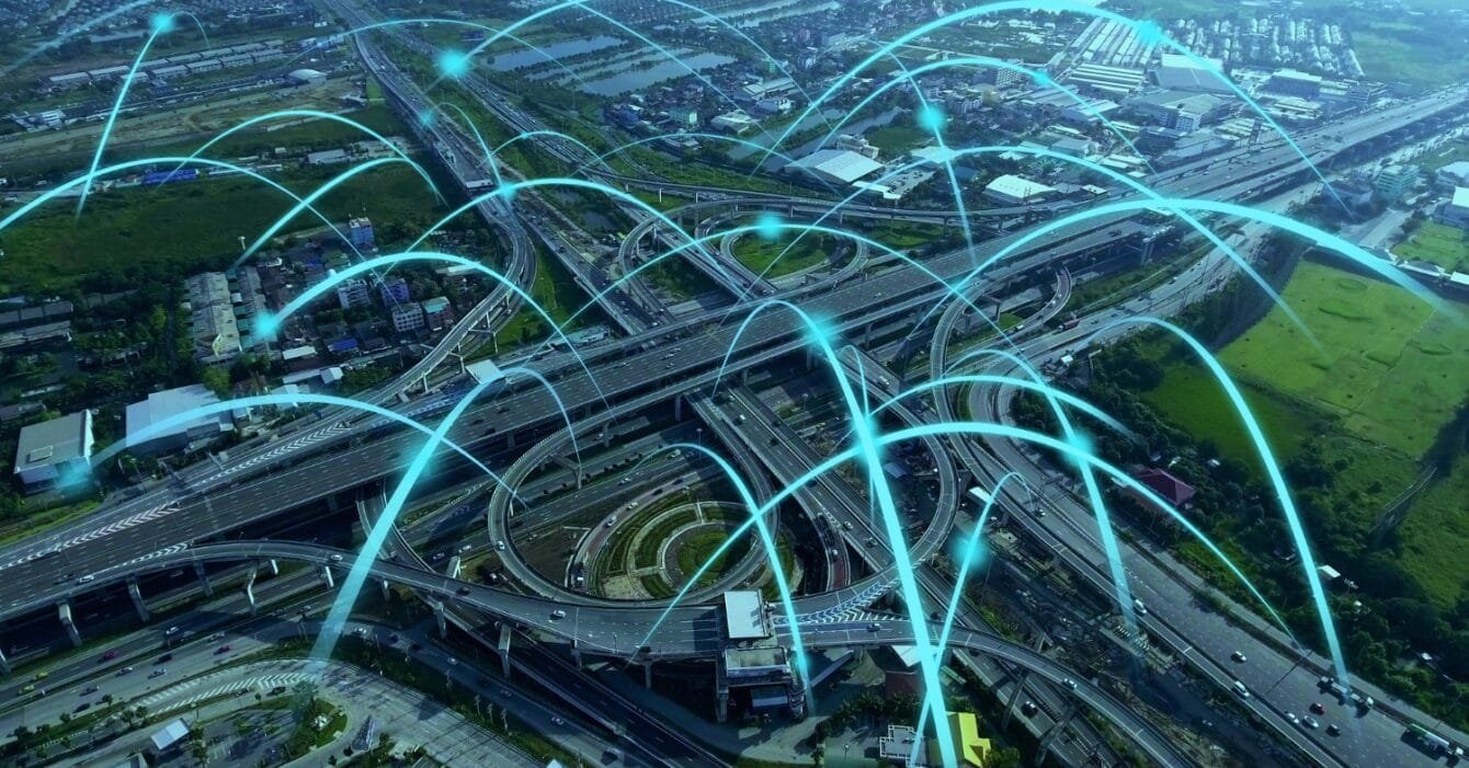 Thailand Infrastructure Connectivity: Aerial view of a highway interchange with blue light trails indicating traffic flow.