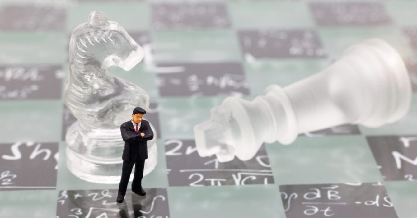 Thailand Construction Financing Challenges: A small figure of a person in a suit on a chessboard with a fallen white king piece.