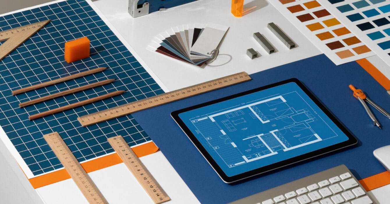 Thailand Digital Construction Tools represented by Desk with drafting tools, color swatches, and a tablet displaying blueprints.