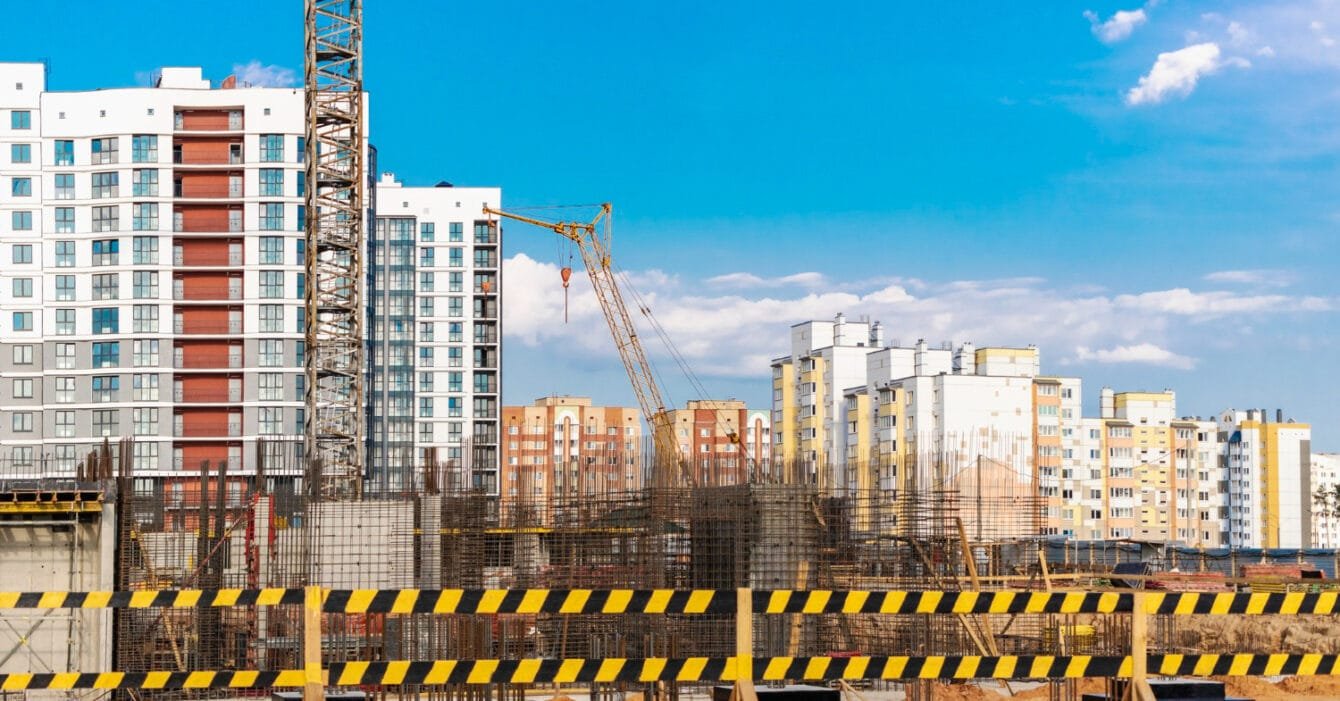 Thailand Construction Safety Standards: Active construction site with crane and buildings against a blue sky.